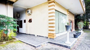 A building with a tiled entrance, a large potted plant, and a motorcycle parked outside. - Super OYO Resident- K Syariah (Medan)