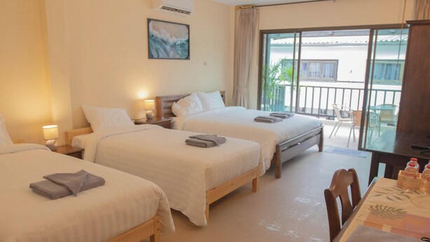 Habitación de hotel con dos camas, un balcón con vistas y una zona de comedor con mesa y sillas.