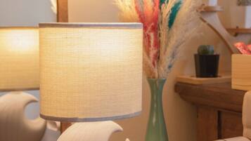 A table with a lamp, a vase with dried plants, and a white object that could be a speaker or a decorative item.