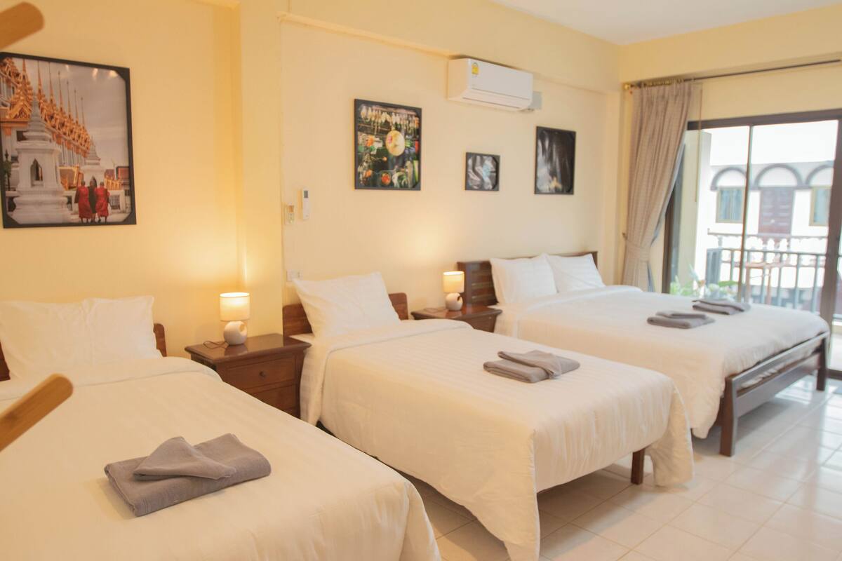 Een hotelkamer met twee bedden, een balkon en kunstwerken aan de wand.