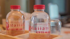 Tres botellas de bebida de Maiam Bungalows en una bandeja de madera.