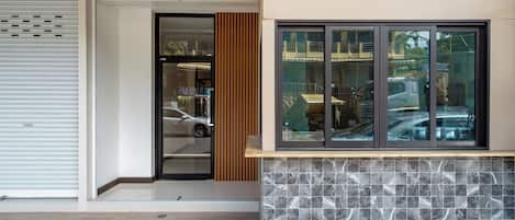 A modern building entrance with a sliding door, a window with a view of the street, and a tiled wall.