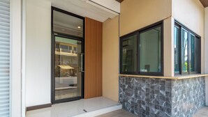 Una entrada moderna con puerta de vidrio, pared de listones de madera y mostrador de baldosas de piedra.