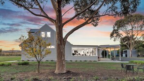 A modern house with a large tree in the front yard, a covered patio, and a garage. - Bulla Homestead  (Bulla)