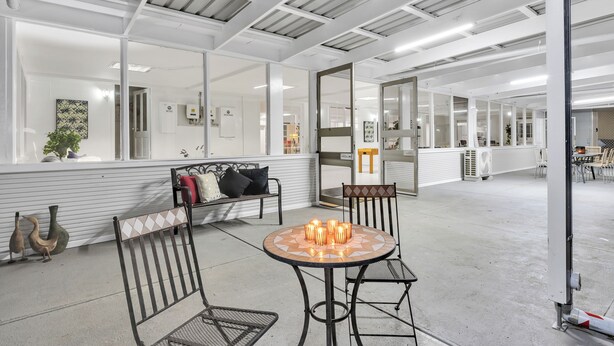 A spacious indoor area with a high ceiling, a round table with candles, and a bench with cushions. - Bulla Homestead  (Bulla)