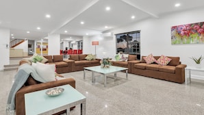 A spacious living area with brown sofas, a glass coffee table, and a large painting on the wall. - Bulla Homestead  (Bulla)