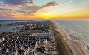An aerial view of a coastal town with residential buildings, a beach, and a pier.