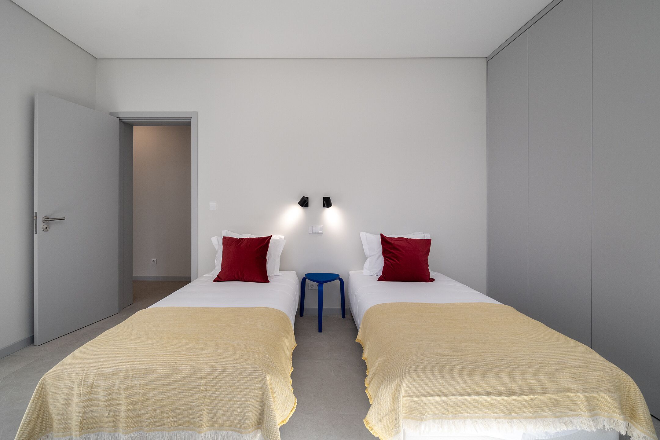 A hotel room with two beds, a small table, and a wardrobe.