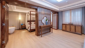 A hotel room with a wooden floor, a bed with a canopy, a bedside table with a lamp, a console table, and a large window with curtains. - fuxueqiuguojiudian (Beijing)