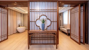 A traditional Japanese-style room with a wooden reception desk, a large white bathtub, and sliding doors. - fuxueqiuguojiudian (Beijing)