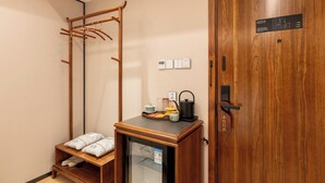 A hotel room with a wooden wardrobe, a small refrigerator, a kettle, and a coat rack. - fuxueqiuguojiudian (Beijing)