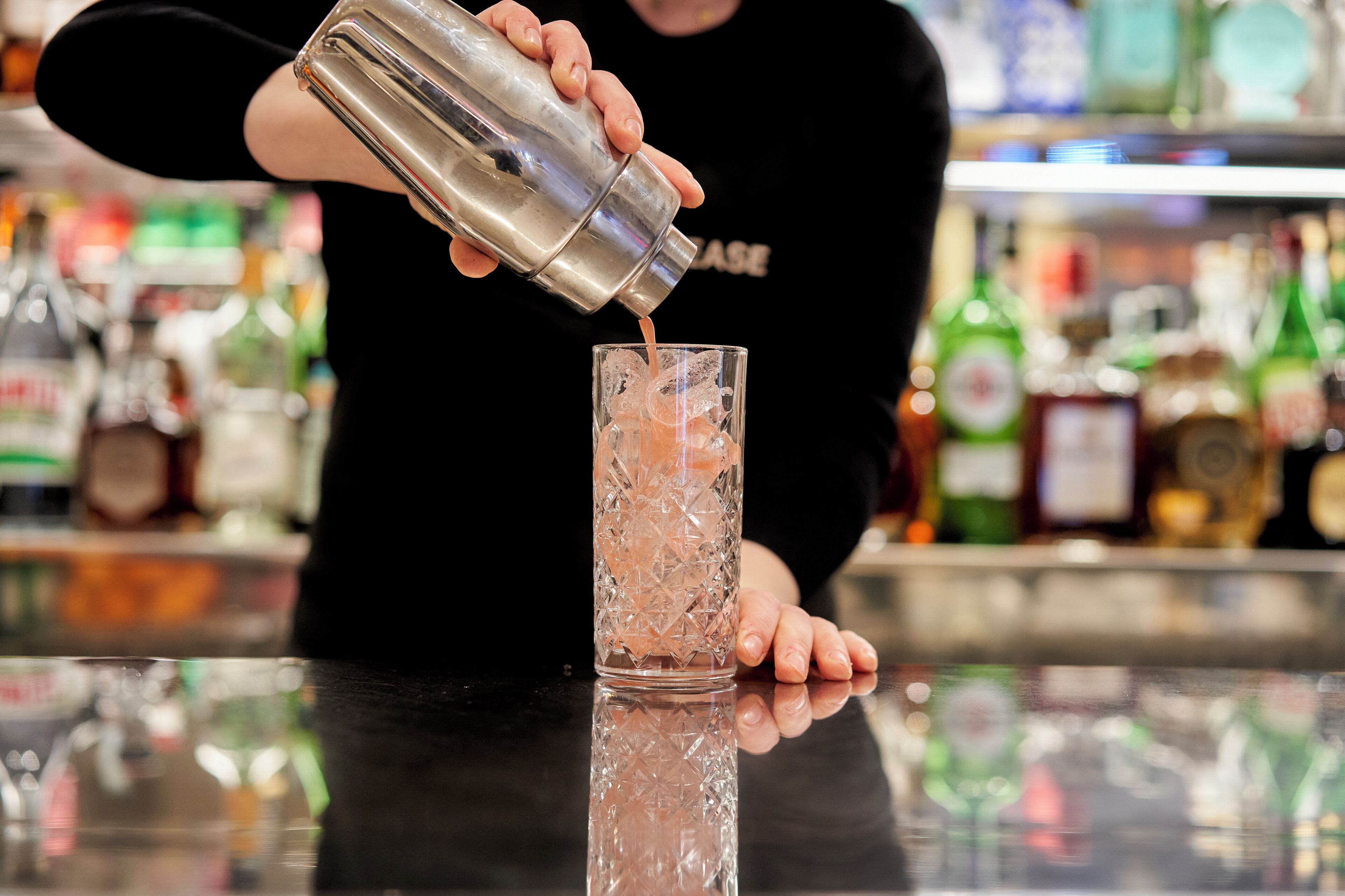 A bartender pouring a drink into a glass.