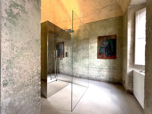 A bathroom with a glass shower enclosure, a painting on the wall, and a window providing natural light. - SUGAR ROOMS Residenza d' Epoca (Arezzo)