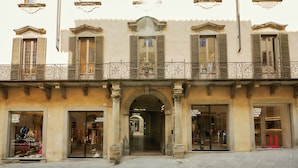 A building facade with multiple storefronts, including a visible shop with a sign that reads "I SMELL SUGAR ONLY T-SHIRT." - SUGAR ROOMS Residenza d' Epoca (Arezzo)