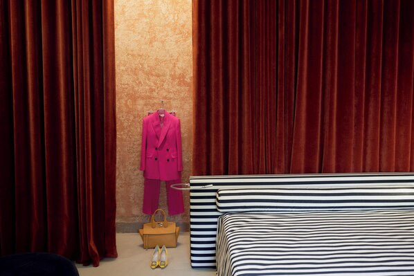 Una habitación con una cama, un traje rosa, un bolso y zapatos amarillos.