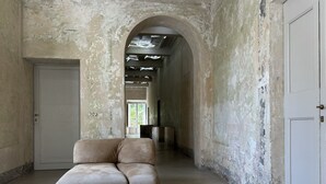 A corridor with a large arched doorway, a white door labeled "202", and a sofa with a geometric pattern. - SUGAR ROOMS Residenza d' Epoca (Arezzo)