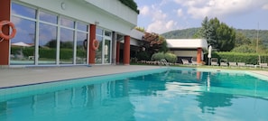 A swimming pool with a clear view of the surrounding area, including a building with large windows and a lifebuoy.