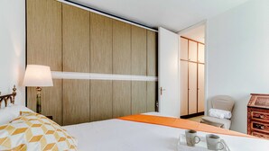 A hotel room with a bed, a nightstand with a lamp, a wooden wardrobe, a chair, and a dresser. - Il Parco (Montorfano)