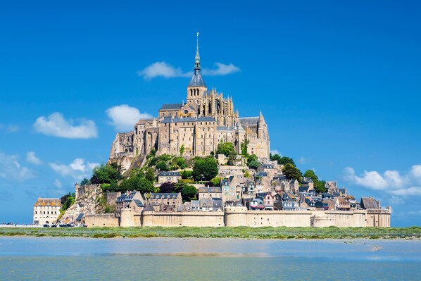 A historic castle with a prominent tower, situated on a hill overlooking a body of water.