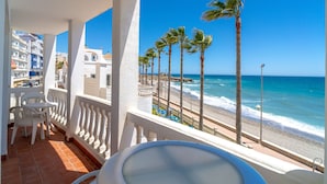 A balcony with a view of the beach, palm trees, and ocean.