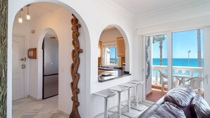 A modern kitchen with a stainless steel refrigerator, a wooden decorative arch, and a bar area with stools.