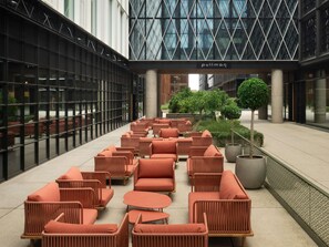 Un espace de détente intérieur moderne, avec des meubles en osier et un grand bac à plantes au centre.