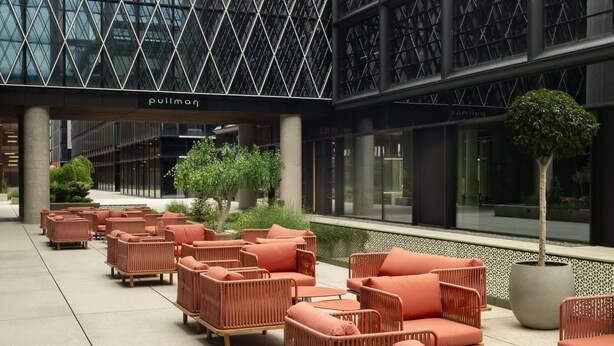 A modern building with a glass facade, outdoor seating area with wicker furniture, and a sign that reads "Pullman". - Pullman Zagreb (Zagreb)