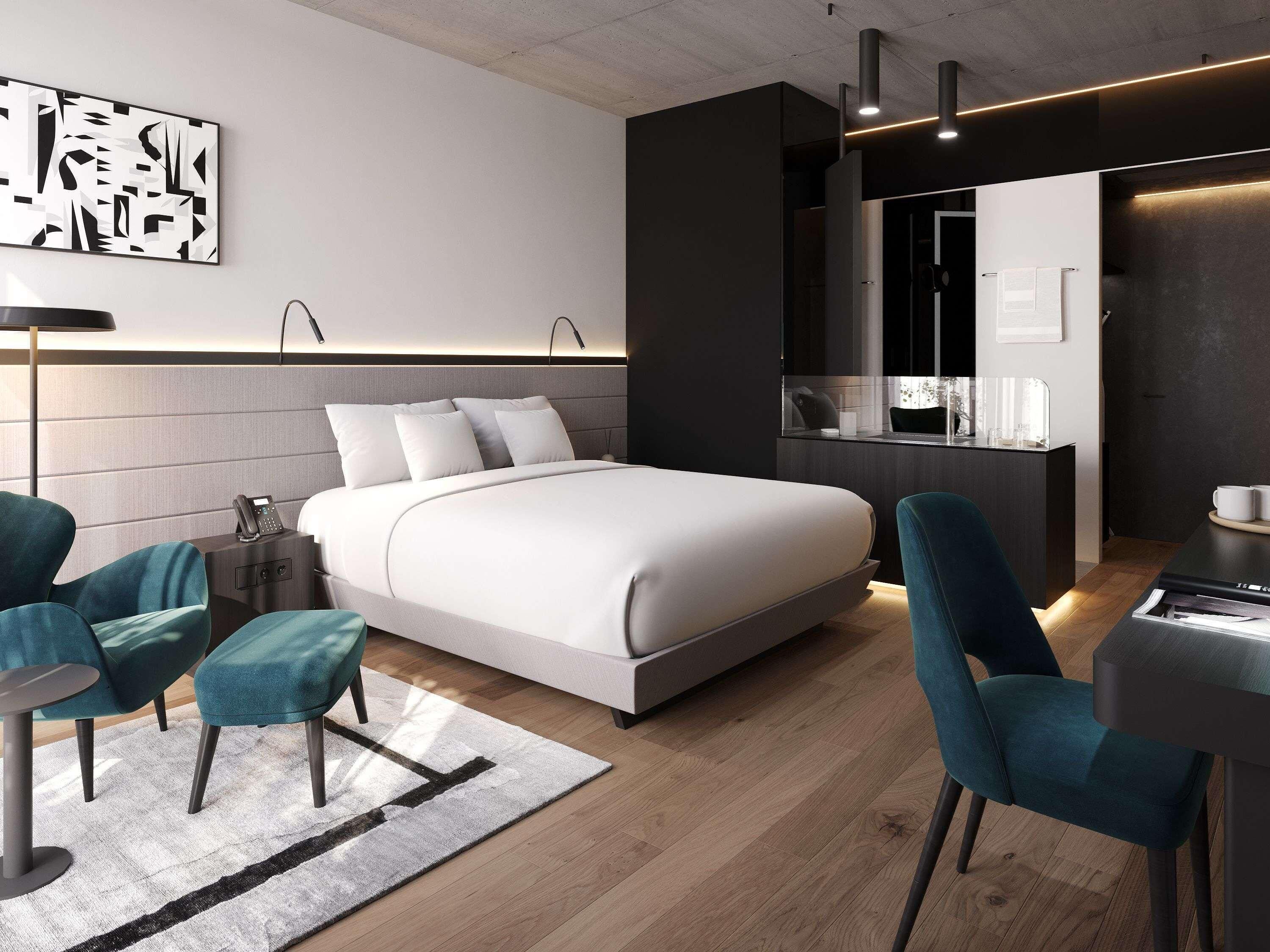 Una habitación de hotel moderna con una cama grande, dos sillones, un escritorio y un minibar.
