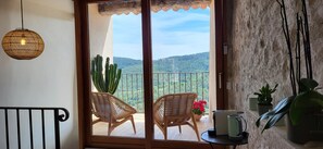 A balcony with wicker chairs, a potted cactus, and a view of a mountainous landscape. - La Belle Histoire (Claviers)