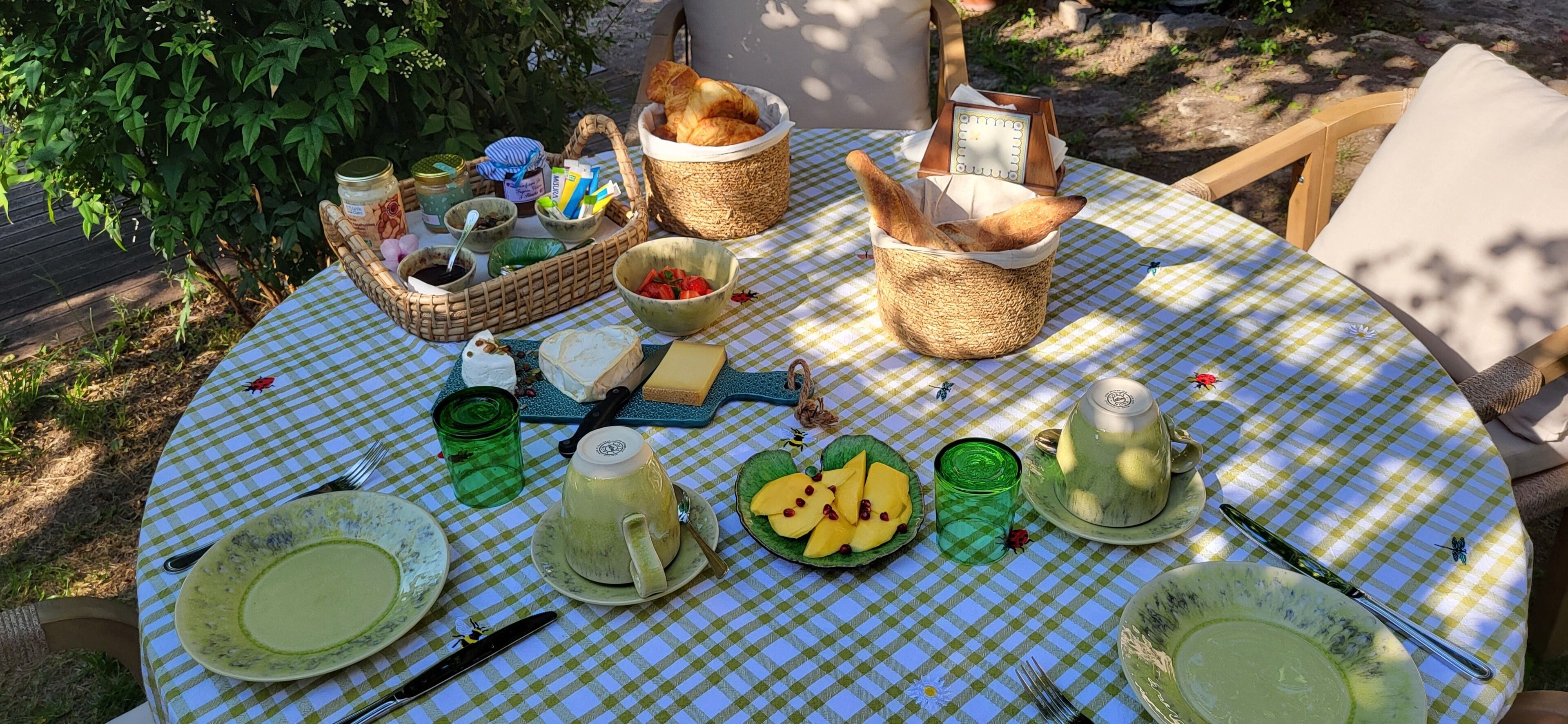 A round table with a checkered tablecloth, various food items, and utensils.