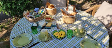A round table with a checkered tablecloth, various food items, and utensils.