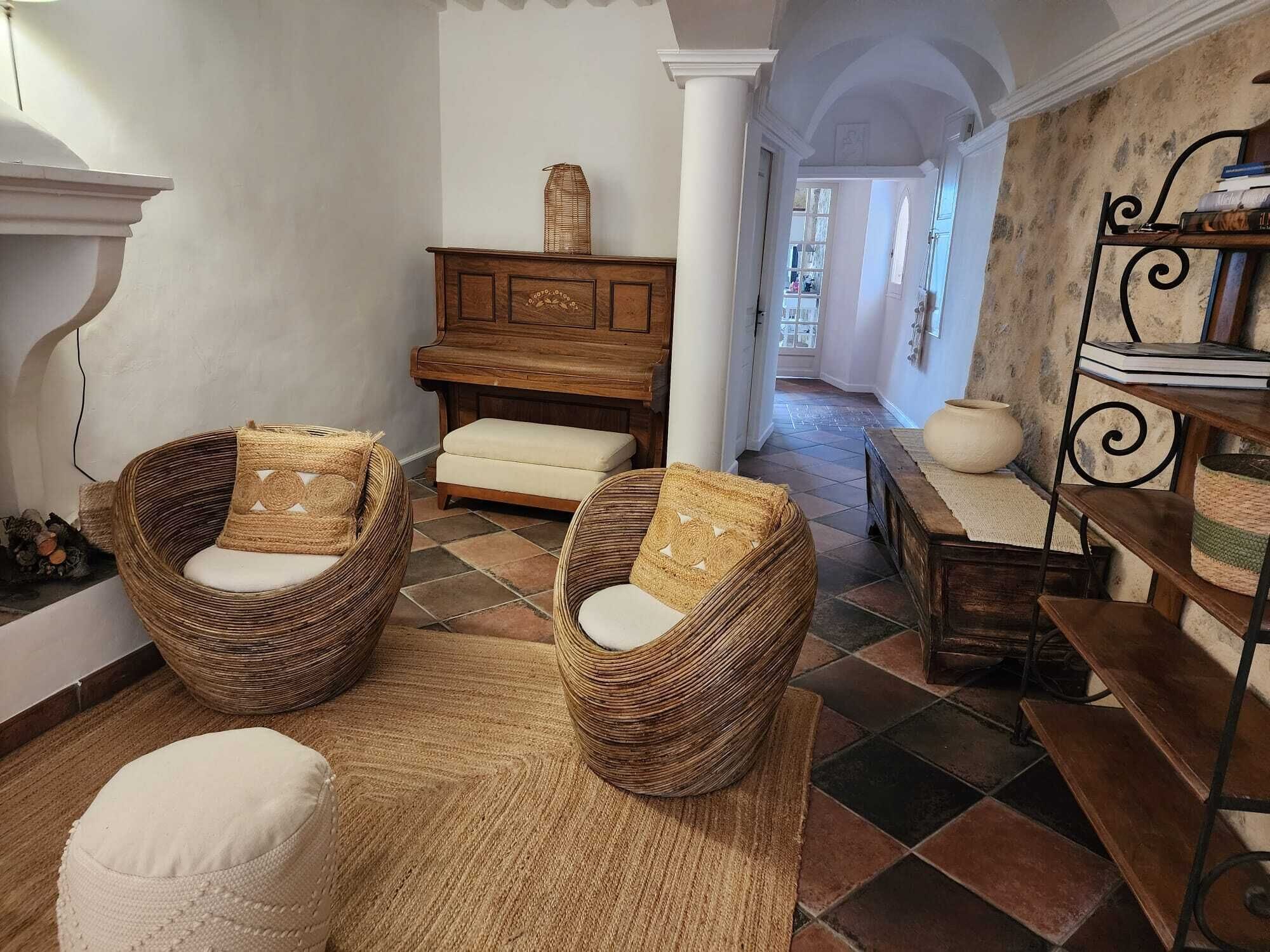 Una habitación acogedora con sillas de mimbre, un piano y una estantería rústica.