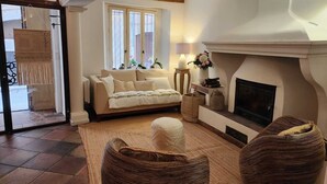 Una sala de estar acogedora con chimenea, un sofá y muebles de mimbre.