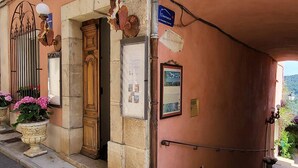 Entrada de un edificio con puerta de madera, un cartel y una placa.