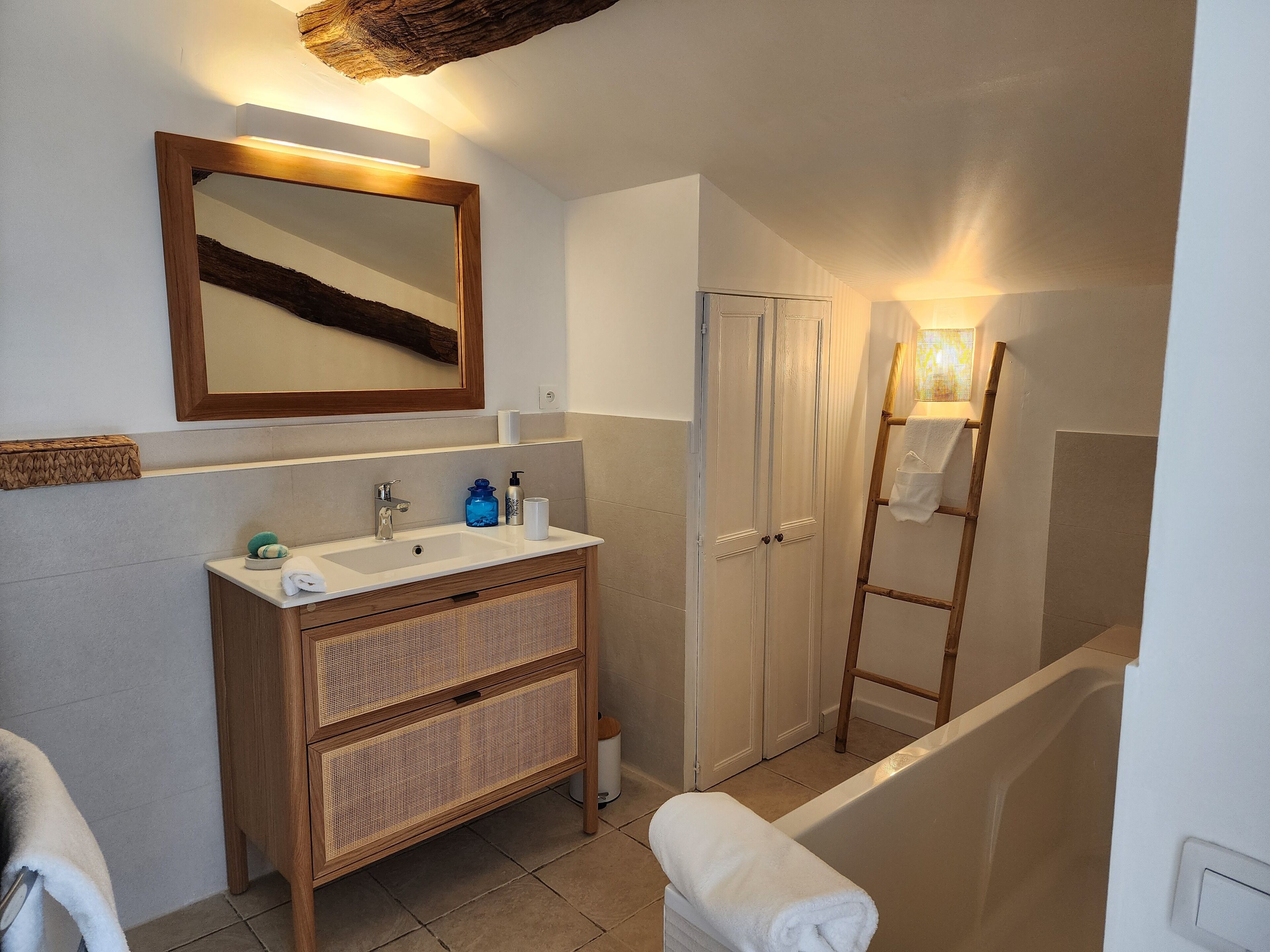 Een badkamer met een houten wastafelmeubel, een spiegel, een wastafel, een toilet en een bad.