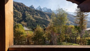 Un balcon en bois offrant une vue sur un paysage montagneux, avec des arbres et une maison.