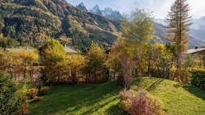 Un paysage montagneux avec une zone herbeuse et des arbres aux couleurs automnales.