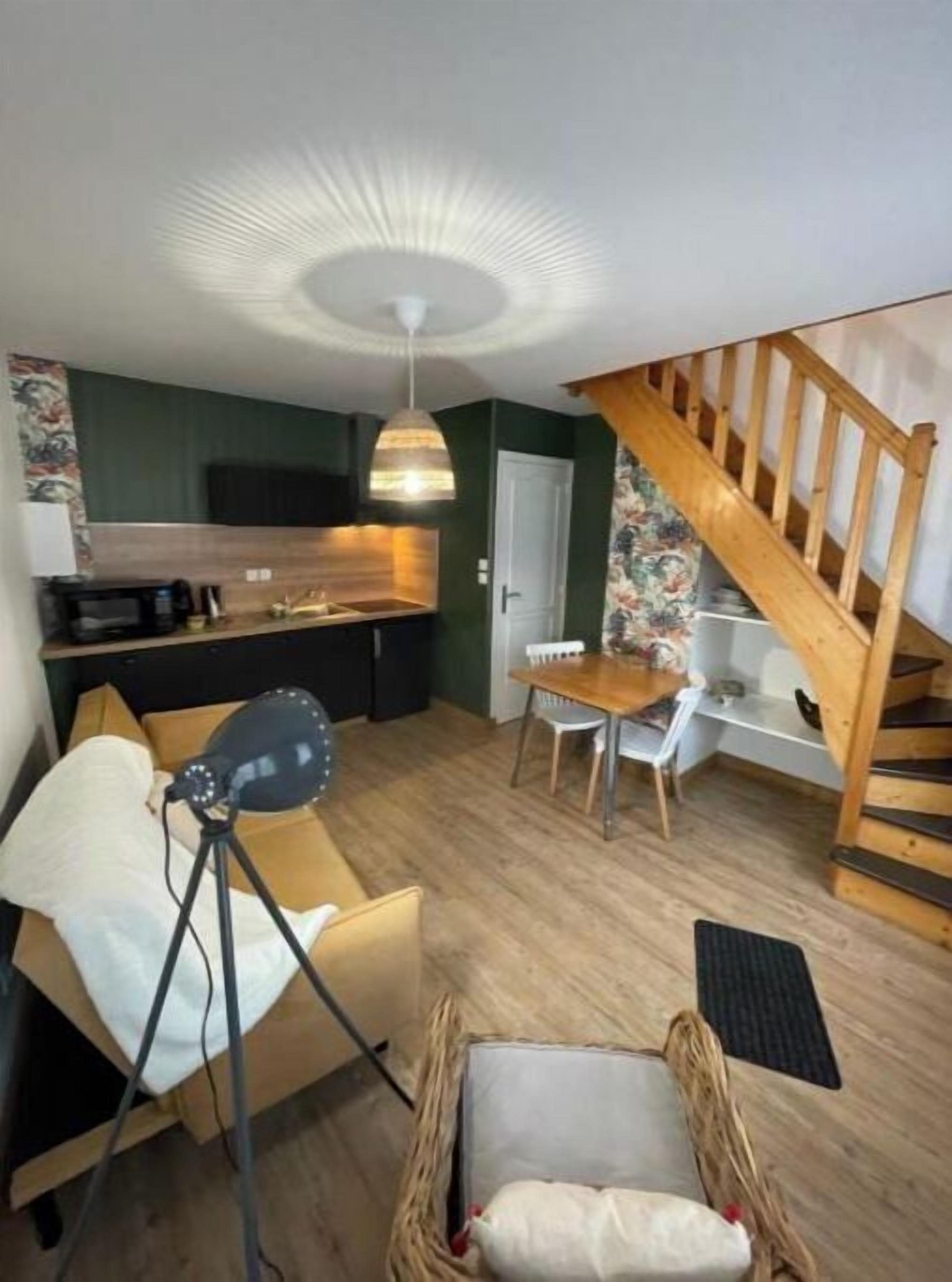 A compact living space with a kitchenette, a dining area, and a staircase.