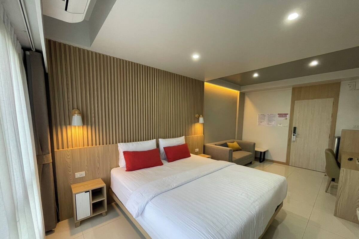 Une chambre d’hôtel moderne dotée d’un grand lit, de tables de chevet, d’un coin salon et d’une armoire.
