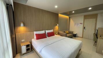 Habitación de hotel moderna con una cama grande, mesitas de noche, una zona de estar y un armario.