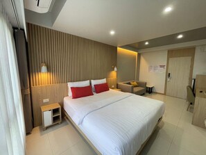 Habitación de hotel moderna con una cama grande, mesitas de noche, una zona de estar y un armario.