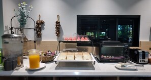 Una preparación para el desayuno con una cafetera, un tostador y una bandeja de fruta.