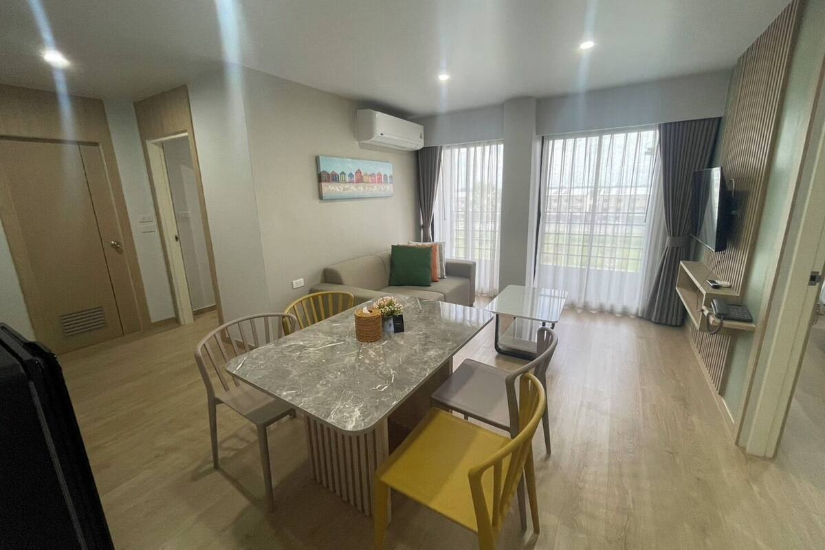 Une chambre d’hôtel moderne dotée d’un coin repas comprenant une table en marbre, des chaises jaunes et un canapé.
