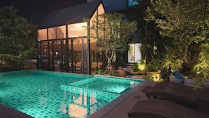 Ein Pool mit Glasboden, umgeben von Liegestühlen und einer gläsernen Struktur mit Sitzgelegenheiten.