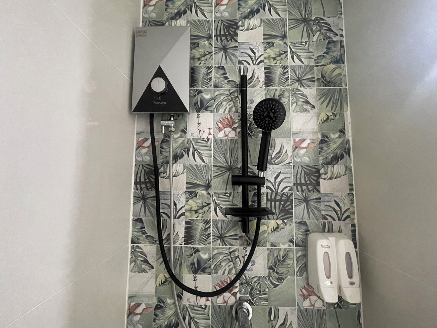 Un baño con ducha, cabezal de ducha de mano y panel de control en la pared.