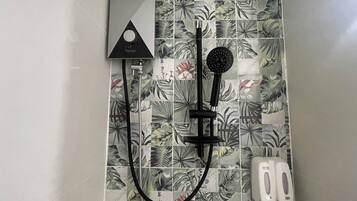 Un baño con ducha, cabezal de ducha de mano y panel de control en la pared.