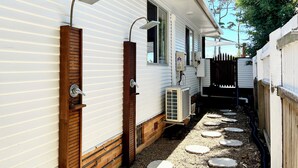 Una casa móvil blanca con puerta de madera, una ventana y un pequeño espacio exterior con piedras para caminar.
