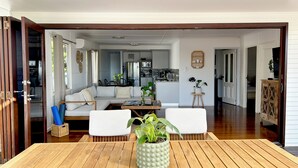 Un amplio salón con una mesa de madera, dos sofás blancos y una planta verde como centro de atención.