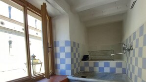 A small kitchen with a window, blue and white checkered walls, and a metal rack.