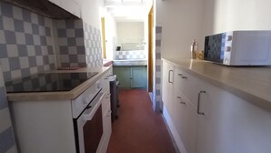A narrow kitchen with a checkered backsplash, a microwave, and a sink.